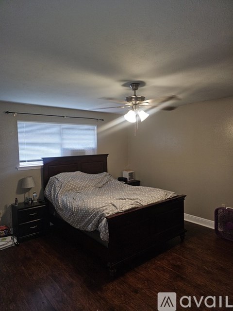 A bedroom with a bed, nightstand, and a ceiling fan.