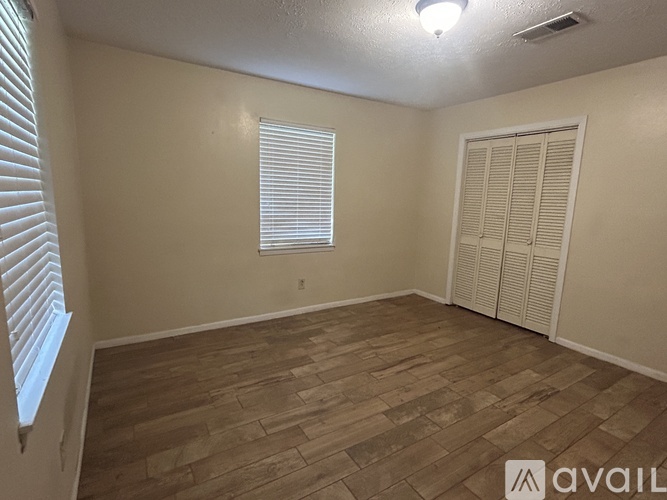 A room with wooden flooring and a window with blinds.