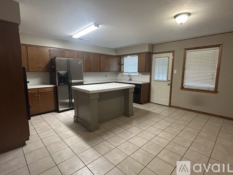 A kitchen with a refrigerator, cabinets, and a counter is available for rent.