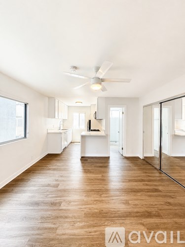 A spacious room with wooden flooring and a ceiling fan.