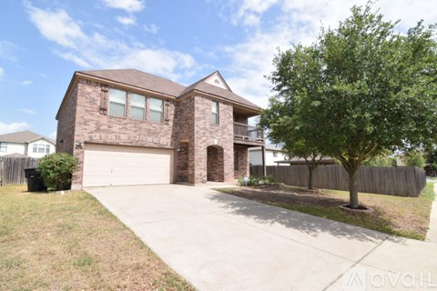 A house with a garage and a tree in front.