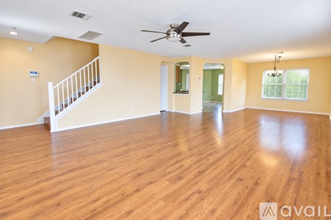A spacious room with wooden floors and a ceiling fan.