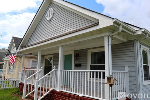A house with a grey siding and a white porch.