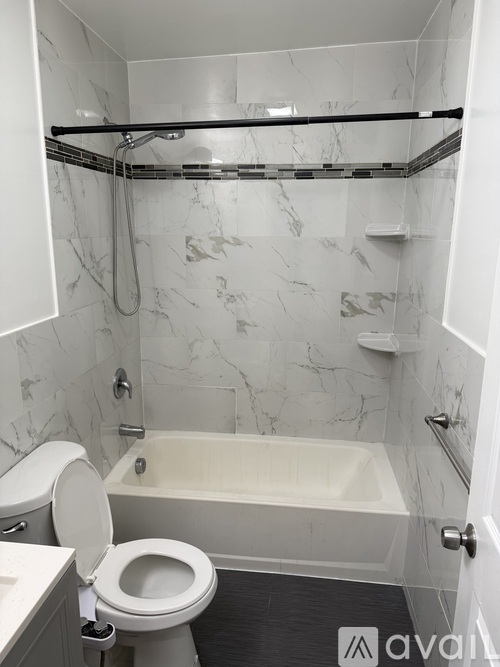 A bathroom with a marble wall and a white bathtub.