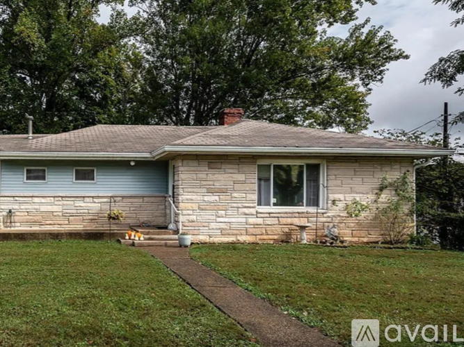 A house with a stone wall and a brown roof.