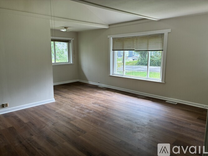 A room with wooden floors and two windows.