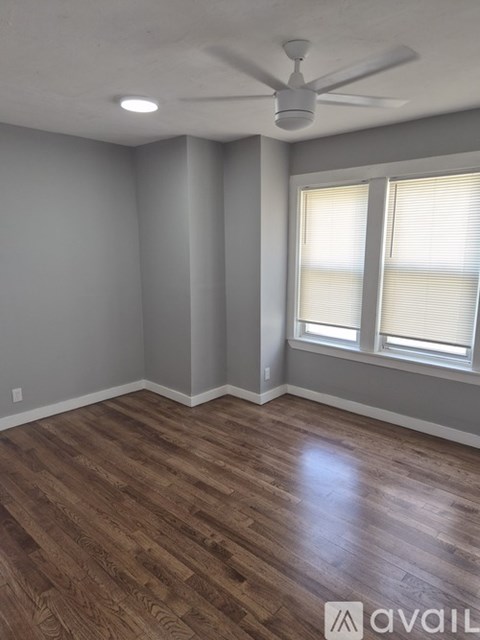 A room with a ceiling fan and wooden flooring.