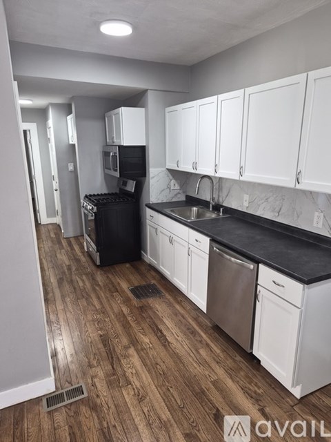 A kitchen with white cabinets and black countertops.