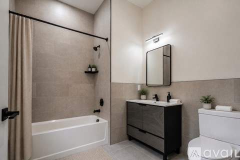 A modern bathroom with a white bathtub, a sink with a mirror above it, and a toilet.