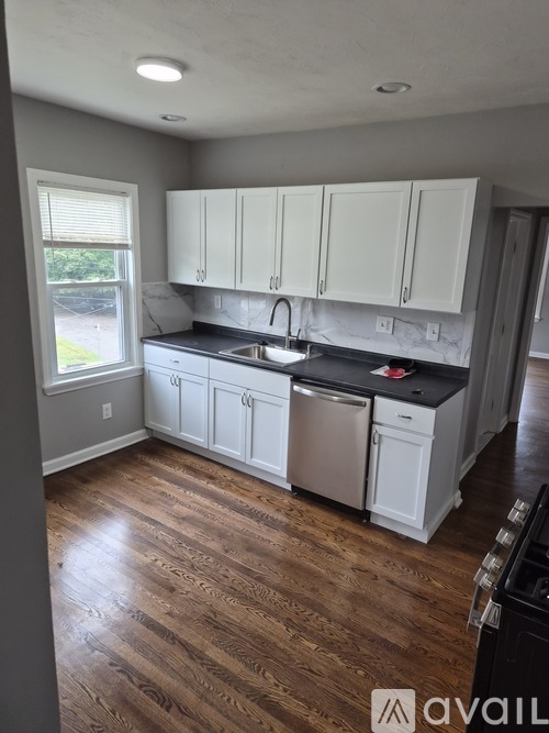 A kitchen with white cabinets and a wooden floor.