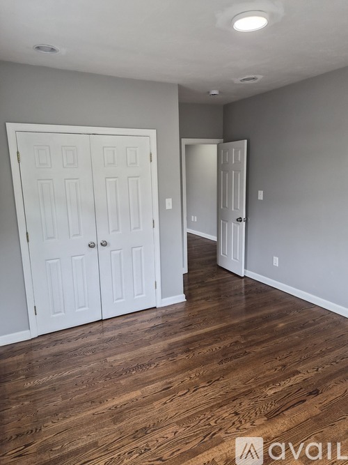 A room with wood floors and two white doors.