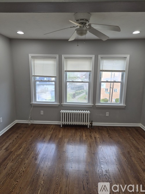 A room with a ceiling fan and three windows.
