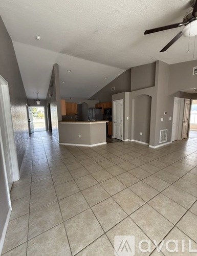 A spacious room with tile flooring and a ceiling fan.