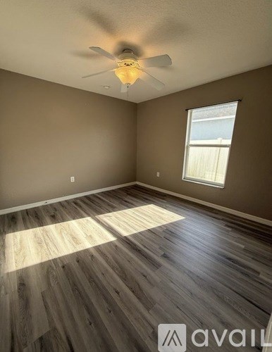 A room with a ceiling fan and wooden flooring.