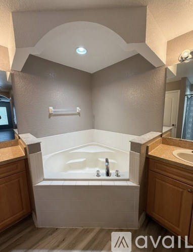 A bathroom with a tub, sink, and wooden cabinets.
