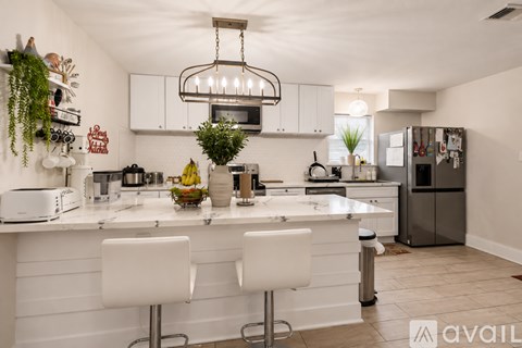 A kitchen with white chairs and a white counter.