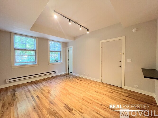 A room with wooden flooring and a window with blinds.