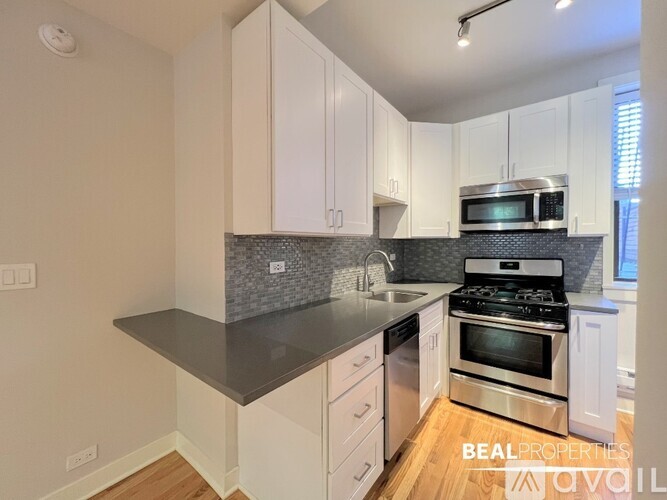 A kitchen with white cabinets and a black countertop.