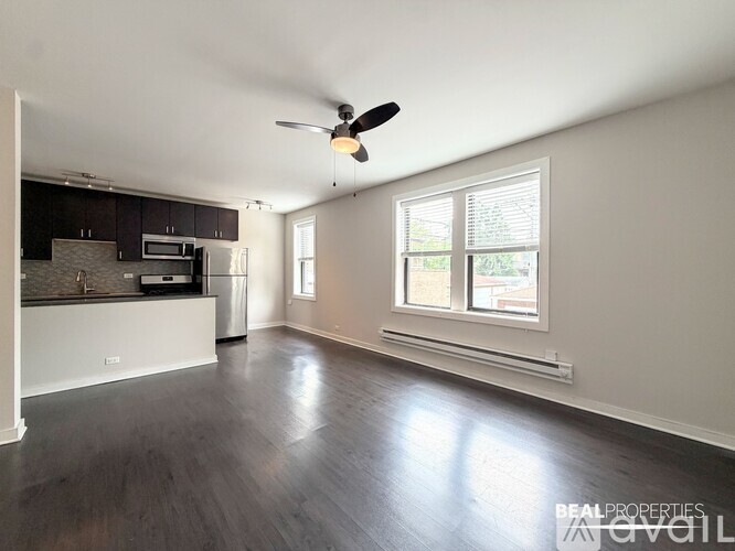 A spacious living room with a ceiling fan and hardwood flooring.