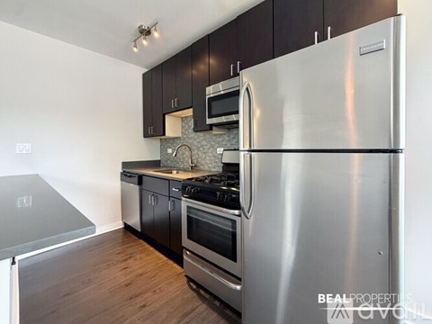 A modern kitchen with a stainless steel refrigerator, microwave, and oven.