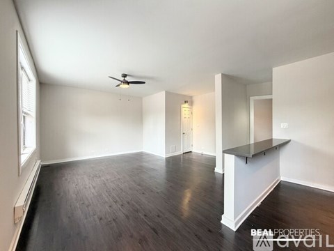 A spacious room with a ceiling fan and wooden flooring.