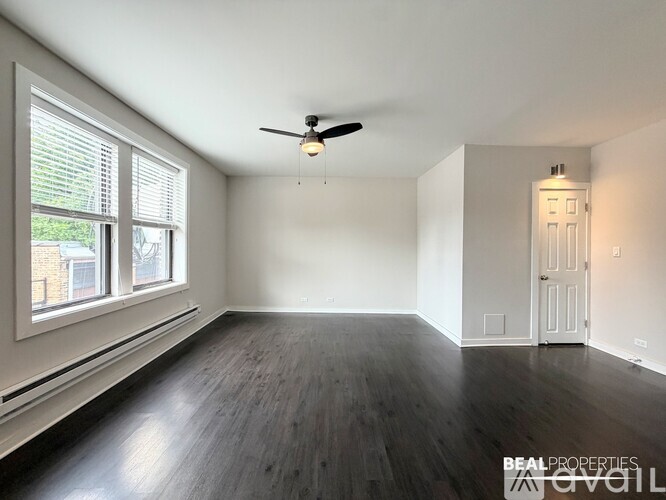 A spacious room with a ceiling fan and wooden flooring.