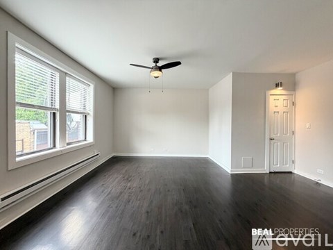 A spacious room with a ceiling fan and wooden flooring.