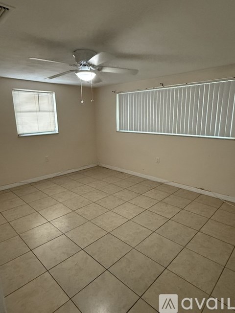A room with a ceiling fan and a window with blinds.