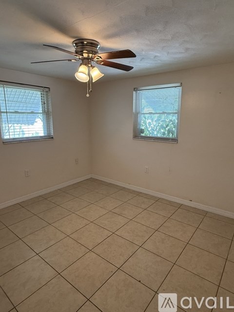 A room with a ceiling fan and two windows.