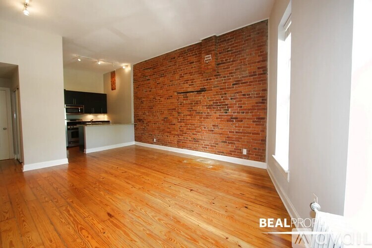 A room with wooden floors and a brick wall.