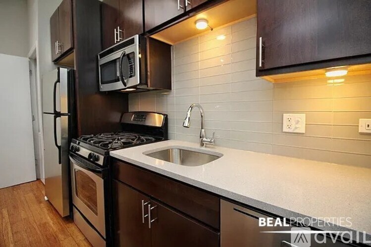 A kitchen with a stove, sink, and microwave.