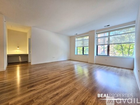 A spacious room with wooden flooring and large windows.