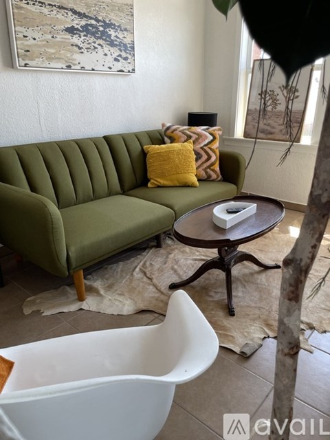 A living room with a green couch and a white chair.