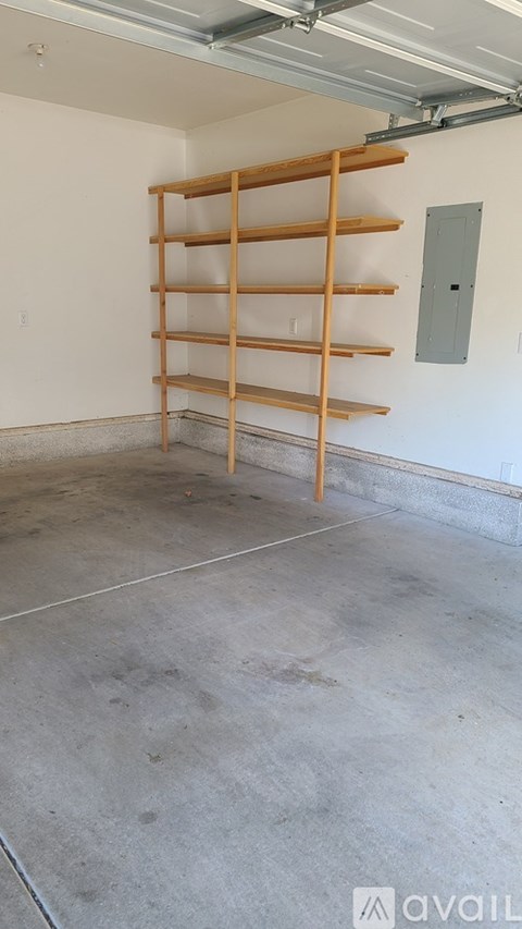 A room with a wall-mounted shelving unit and a concrete floor.