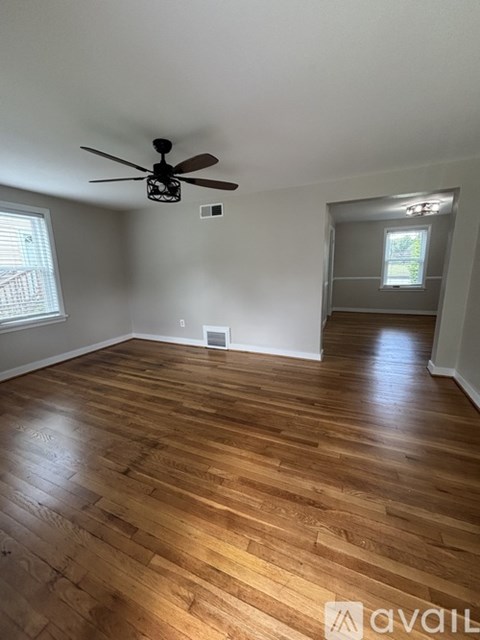 A room with a ceiling fan and wooden flooring.