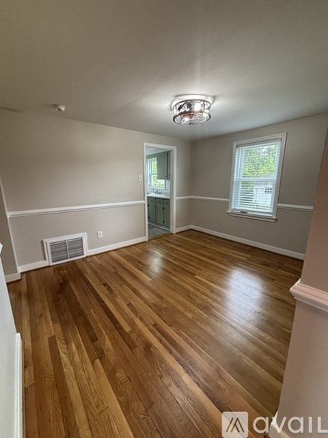 A room with wooden flooring and a window with blinds.