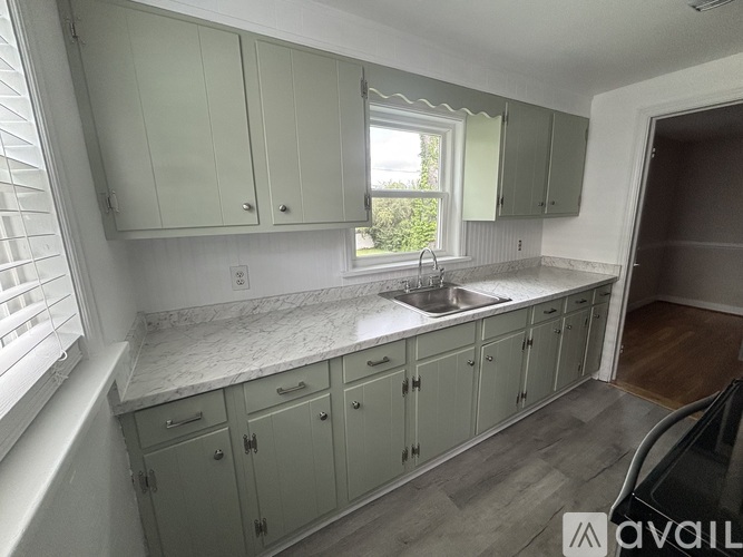 A kitchen with green cabinets and a marble countertop.