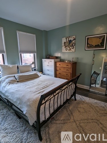 A bedroom with a bed, dresser, and window.