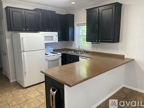 A kitchen with black cabinets and a white refrigerator.