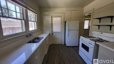 A kitchen with a stove, sink, and cabinets.