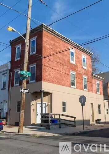 A street view of a red brick building with a green street sign in front.