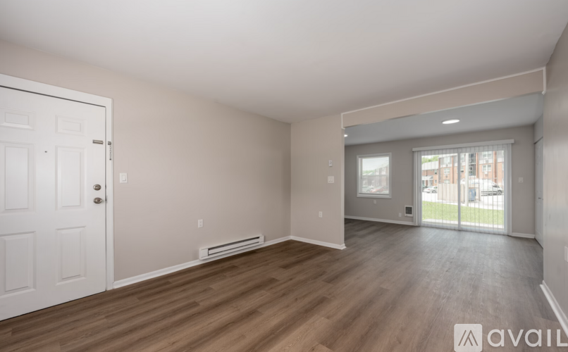 A spacious room with wooden floors and a white door.