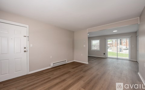 A spacious room with wooden floors and a white door.