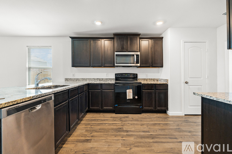 A kitchen with dark wood cabinets and a stainless steel dishwasher.