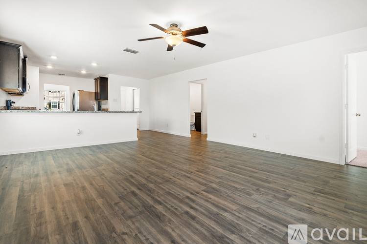 A spacious room with wooden flooring and a ceiling fan.