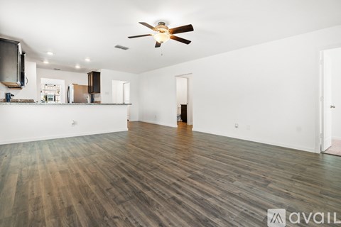 A spacious room with wooden flooring and a ceiling fan.