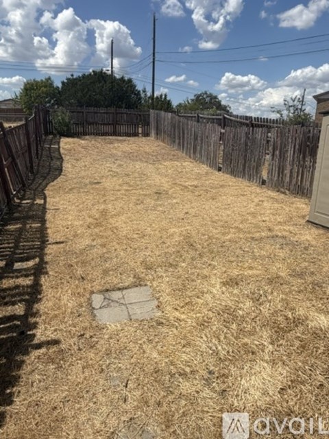 A backyard with a wooden fence and a patch of grass.