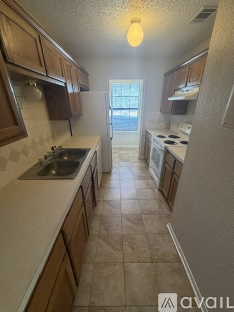 A kitchen with wooden cabinets and a tiled floor.
