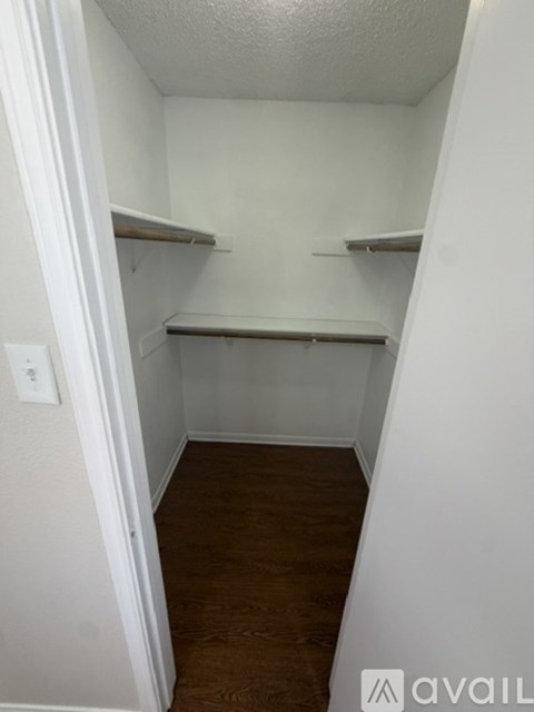 A small, empty room with shelves and a wooden floor.