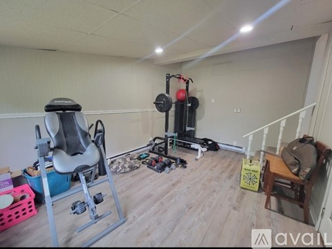A gym room with a weight bench, a chair, and a bag of equipment.
